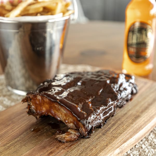 Smoke Shack BBQ ribs with sauce, a bucket of fries, and a bottle of beer.